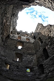 Torre in pietra parzialmente distrutta.  Possiamo indovinare i diversi piani ora mancanti.