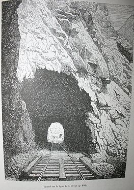 Fotografía en blanco y negro del exterior de un túnel, cuyo final se puede ver.