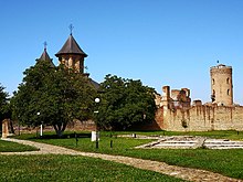 Arka planda bir kilise ile küçük bir tepe üzerinde taştan harap duvarlar,