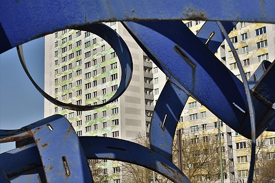 Hochhausfassade in Berlin-Friedrichsfelde. Im Vordergrund Stahlskulptur Handelundwandel von Erika Klagge.