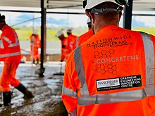 Construction workers in orange hi-vis jackets pouring concrete