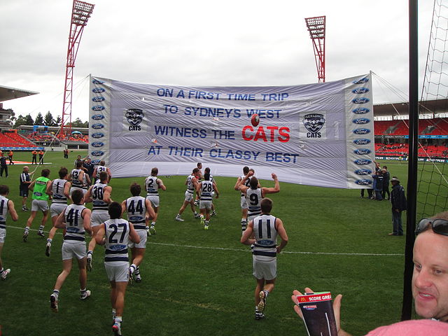 Geelong players prepare to break a banner, which is created by its supporters, before a match against Greater Western Sydney in June 2013.