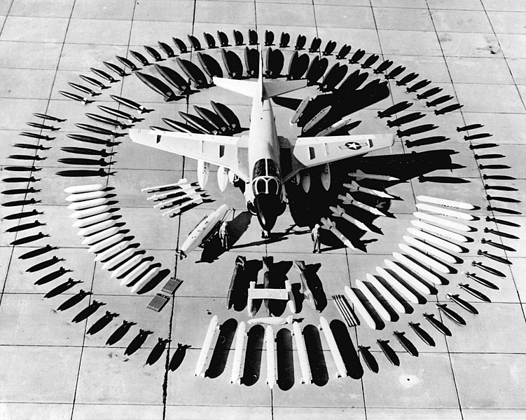 A Grumman A-6A Intruder (then designated A2F-1) with an array of possible ordnance. Outside ring: in front of the A-6 are five mock-ups of multiple ejector racks. To the right and left are 46 Mk 81 113 kg (250 lb) bombs. The circle is closed by 30 Mk 82 227 kg (500 lb) bombs. Second ring: In front of the plane are "five classified shapes" (napalm canisters and/or nuclear weapons?). To the right 13 LAU-10 rocket launchers with four 12.7 cm (5 in) Zuni rockets each are arrayed, on the opposite side 13 Aero 7D (LAU-3/A) rocket launchers with 19 7 cm (2.75 in) are displayed. To the right and left of the horizontal stabilizers are 15 Mk 83 454 kg (1.000 lb) bombs, and 12 Mk 79 fire bombs are displayed behind the aircraft. Inner ring: behind the left wing (with the national insignia) are three Aero 8A practice bomb containers, on the opposite side five Mk 84 907 kg (2.000 lb) bombs are displayed. In front of the left wing are five AGM-12A Bullpup air-to-ground missiles, in front of the right wing are four AIM-9B Sidewinder air-to-air missiles and a Douglas D-704 Buddy-Buddy refueling tank with extendable snorkel (a.k.a. Buddy Store). The aircraft itself carries four 1.137 l (300 gal) tanks.