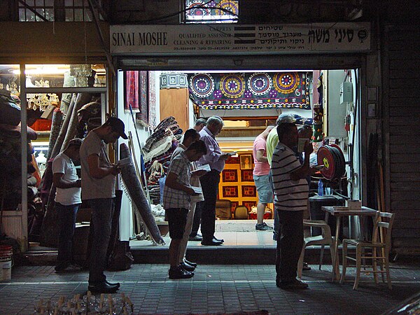 Jews stop to pray Maariv (evening prayer) while at a Tel Aviv flea-market shop