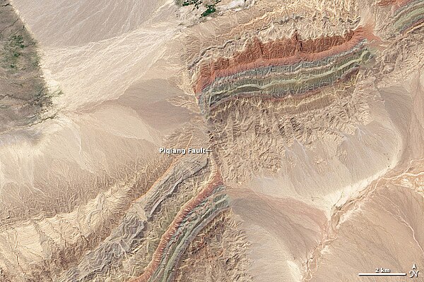 Satellite image of a fault in the Taklamakan Desert. The two colorful ridges (at bottom left and top right) used to form a single continuous line, but