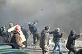 Protesters throwing brick pavement in the direstion of internal troops line covered under smoke of burning tires. Clashes in Ukraine, Kyiv. Events of February 18, 2014