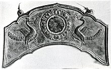 Flat metal sheet in an arc shape with embossed relief of two birds.