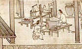 Two workers soak cocoons in a large vat of water, in front of a weaving loom.