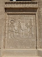 Relief on a screen wall between columns at Dendera, with images of marsh plants at the base, torus moldings framing the relief, and a cavetto cornice with a winged sun emblem topped by a frieze of uraei. First to second century AD.[64]