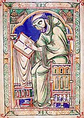 A tonsured monk writing at a desk