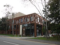 A modern, cuboidal building with rust-brown metal walls decorated with large white cogwheel motifs