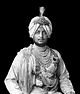 A man wearing traditional, elaborate Indian princely dress and a turban