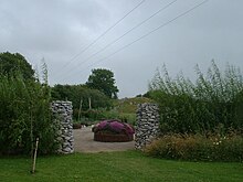 Shows a opening through a stone wall, looking into the autumn gardens, focusing on flowering "harvest basket".