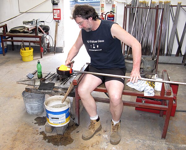 A stage in the manufacture of a Bristol blue glass ship's decanter. The blowpipe is being held in the glassblower's left hand. The glass is glowing ye