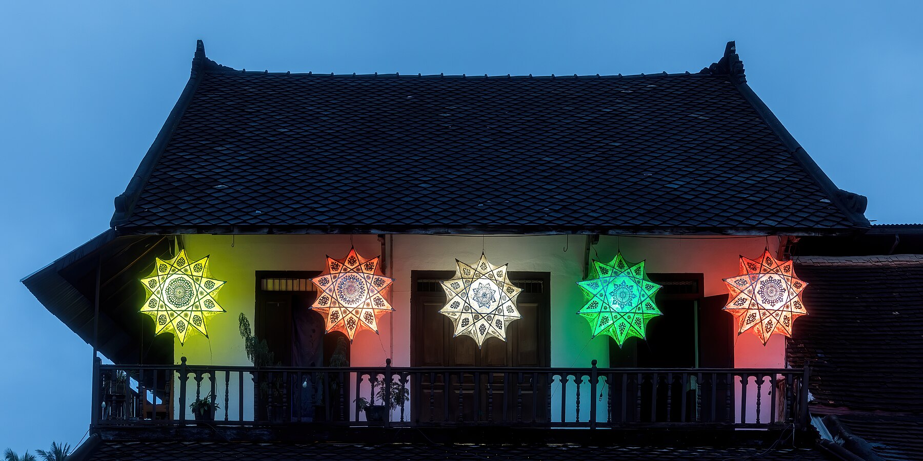 Colorful star-shaped lanterns hanging on a building at blue hour in Luang Prabang Laos