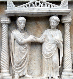 Couple clasping hands in marriage, idealized by Romans as the building block of society and as a partnership of companions who work together to produce and rear children, manage everyday affairs, lead exemplary lives, and enjoy affection Dextrorum iunctio edited.JPG