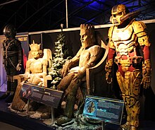 Several costumes and creatures in the episode, the spacesuit from the start of the episode, the Wooden Queen and King, and the Harvest Ranger costumes, on display at the Doctor Who Experience. Doctor Who Experience (15083083522).jpg