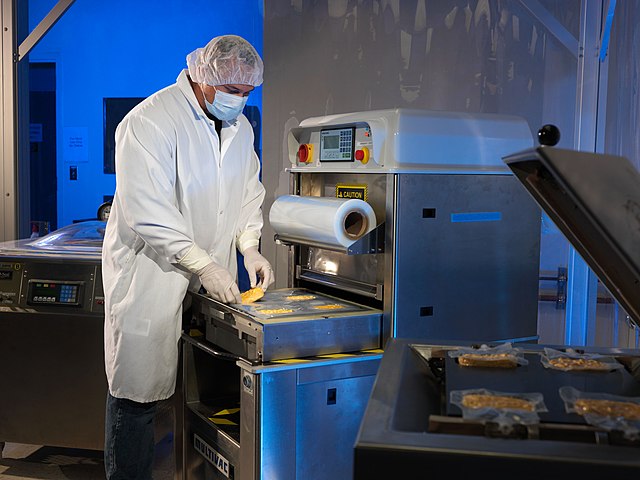 Man holding a small pastry inside plastic wrappings