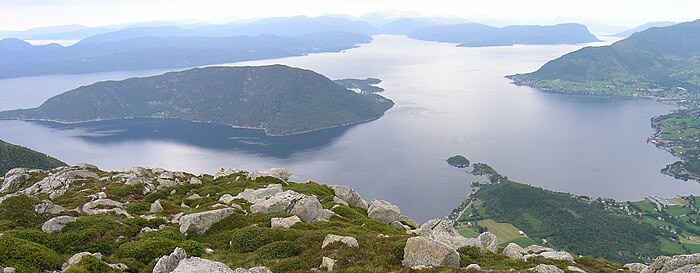 Kvinnheradsfjorden fra Snilstveitøy (i venstre halvdel af bildet) og innover til Varaldsøy som splitter fjordløbet i Øynefjorden (vestlige fjordarm) og Sildafjorden. Nede til højre skimtes byen Dimmelsvik, og i højre billedkant Seimsfoss og Rosendal. Set fra Solfjellet mellem Uskedalen og Omvikdalen.