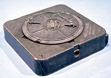 An inert M19 anti-tank mine. The arming switch is set to "S" (i.e. safe) so the fuze is not armed. A secondary fuze well (with the cap removed) is visible on the side of the mine M19 anti-tank mine.jpg