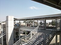 Blick auf eine Fußgängerbrücke mit zwei Treppenhäusern, die sich jeweils auf der gegenüberliegenden Straßenseite befinden.Außerdem befindet sich neben einer dieser Treppen ein Aufzugsschacht.