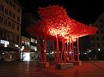 The Neuhauser Straße in the city centre of Munich at night with the wooden sculpture "The Traveller" by Arne Quinze.