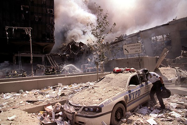 NYPD Sergeant searching through a cruiser covered in debris during 9/11