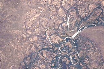 Fotografía satelital de un tramo del Río Negro en Argentina.  Las generaciones sucesivas de meandros y barras de puntos son claramente visibles.  La franja de vegetación de ribera que coincide con las márgenes del cauce actual es claramente visible, denotando una densidad de biomasa mucho mayor que la del interior.