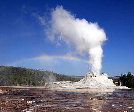 Eruption of Castle Geyser, Yellowstone National Park, with double rainbow seen in the mist