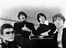 A black-and-white picture of the Velvet Underground, with band member Morrison's hands directing to a vinyl copy of the record