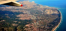 Vista de la zona, con la ciudad de Barcelona al fondo, el aeropuerto del Prat a la derecha de la imagen y, en primer plano, otros municipios y localidades del área metropolitana de Barcelona, con el núcleo de Gavá junto al de Viladecans, ambos en la parte central de la imagen.