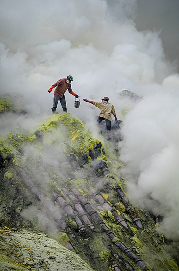 Mineração tradicional de enxofre no vulcão Ijen, Java Oriental, Indonésia. Esta imagem mostra as condições perigosas e difíceis que os mineiros enfrentam, incluindo a fumaça tóxica e quedas altas, bem como a falta de equipamentos de proteção. Os tubos sobre os quais estão colocados servem para guiar os vapores de enxofre e condensá-los, facilitando (bem, pelo menos relativamente) a produção. (definição 1 656 × 1 656)