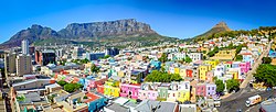 Кейптаунның Бо-Каап аймағы алдыңғы жағында ерекше пастельді түсті үйлермен, қала орталығы сол жақта, ал артқы жағында Үстел тауы бар.