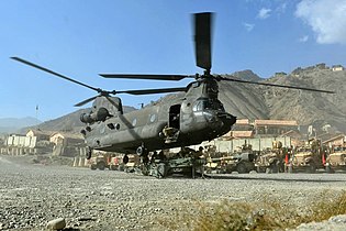 Um helicóptero CH-47 Chinook transportando, via cabo, um M777