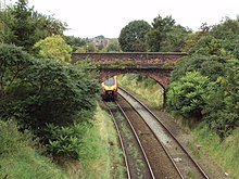Photographie en couleurs présentant les abords boisés d'une voie ferroviaire.