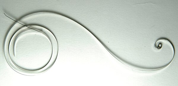 An uncoiled modern watch mainspring.