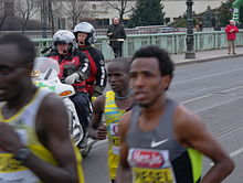 John Korir Kipsang (half hidden behind Amanuel Mesel) crossing the Cechuv most a few minutes before finishing the 2013 Prague Half Marathon Prague Half Marathon 2013 - leading group crossing Cechuv most 06.JPG