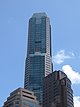 Ground-level view of 70-storey building. The exterior has a reddish hue with dark windows. The building tapers slightly at two points.