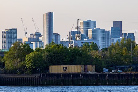 The emerging cluster in Stratford in April 2023 as viewed from Greenwich Peninsula. Stratford has been undergoing regeneration, associated with the 2012 Summer Olympics, which largely took place in Queen Elizabeth Olympic Park to the west of the cluster. Seen on the left is 150 High Street at a height of 135m. The tallest building in the cluster, Manhattan Loft Gardens at 143m, is seen at the back.