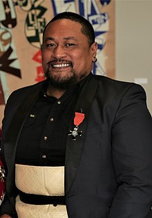 head and shoulders of Tanu smiling at the camera, on his suit jacket is a medal