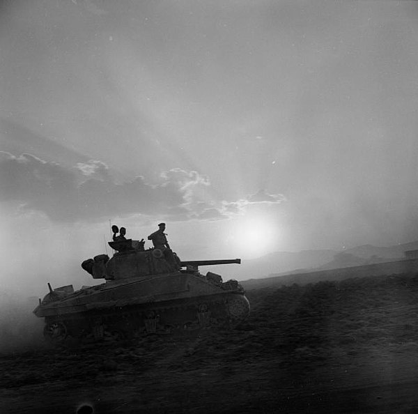 A Sherman tank of 'A' Squadron, 50th Royal Tank Regiment, silhouetted by the setting sun, Sicily, 1 August 1943.