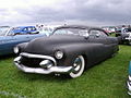 A mild kustom '49 Merc in progress. Note the deep chop, dagmars, '55 Cad grille, wide whites, frenched headlights, Appletons, and vee-butted windshield.