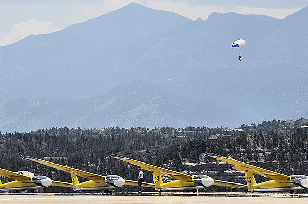 Cadet parachuting out of airplanes over a lineup of gliders