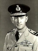 Head-and-shoulders portrait of man in light-coloured military uniform with ribbons and pilot's wings on chest, wearing dark peaked cap