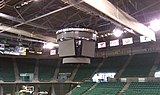 Arena scoreboard hanging in an empty venue with banners and seats visible