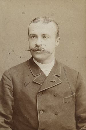 Portrait photograph of a young man wearing a military uniform with a prominent moustache