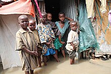 Children are photographed outside their flooded makeshift home in Kismayo, Somalia, in 2014. Environmental factors and anthropogenic climate change have significantly altered the lives of IDPs in Africa. Children seen at their submerged makeshift house in a Kismayu IDP camp.jpg