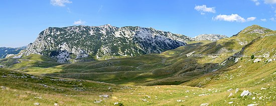 Altopiani ricoperti di erba, senza costruzioni umane, a parte una strada che si snoda sul lato del rilievo.