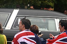 People draped in the Flag of New Zealand as Hillary's hearse passes