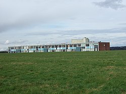 A photo of a long building taken from a field nearby